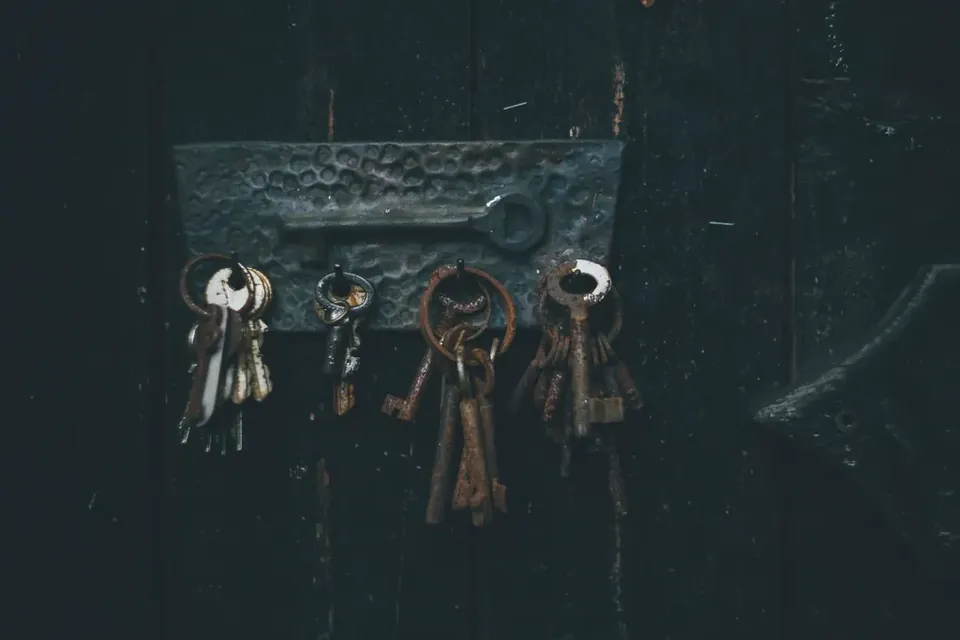 Several bunches of old iron keys hanging from a hammered metal plate