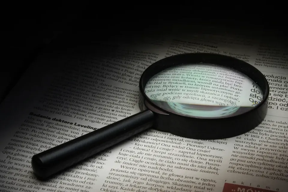A magnifying glass lying on a newspaper under a spotlight